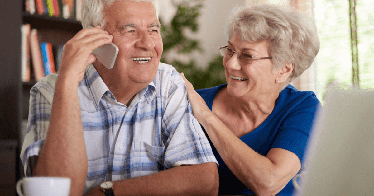 Elderly couple smiling and enjoying a conversation about senior living leads management indoors.