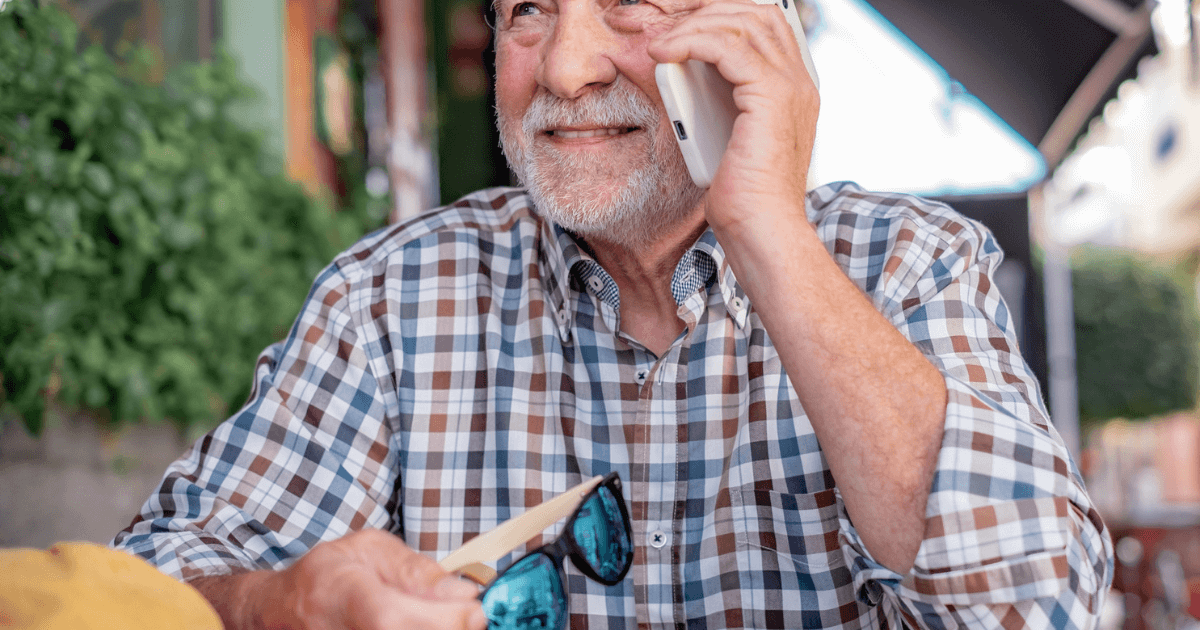 An older man engaging in lead nurturing strategy sales calls while talking on a cell phone.